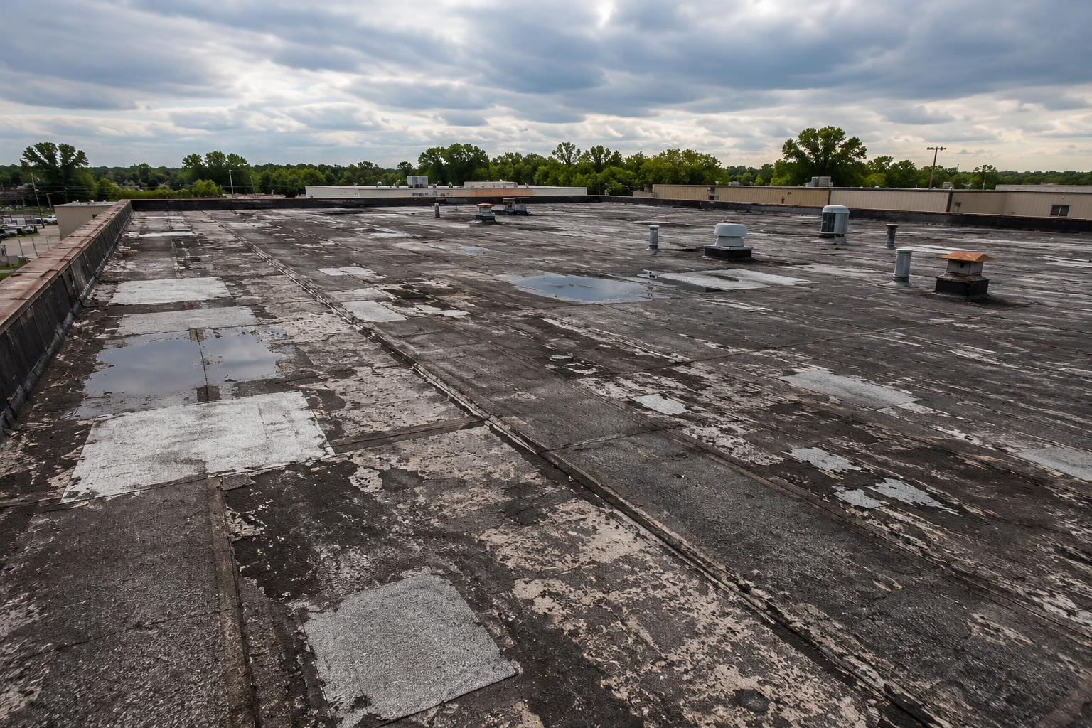 Aging commercial flat roof with weathered membrane and previous repairs